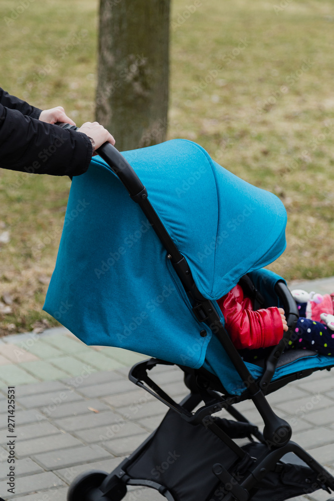 Fototapeta premium The girl is holding a baby carriage with a child in the early morning.