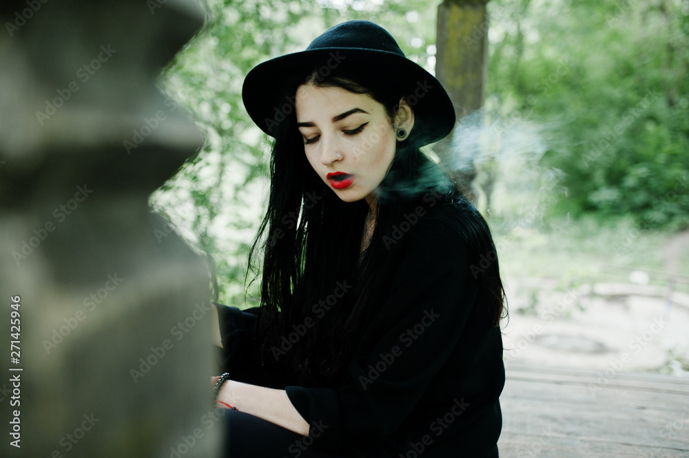 Sensual smoker girl all in black, red lips and hat. Goth dramatic woman smoking thin cigarette. Sensual smoker girl all in black, red lips and hat. Goth dramatic woman smoking thin cigarette.