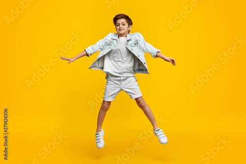 Smiling youngster in stylish outfit leaping up