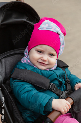 Little girl sitting in a baby carriage on the street