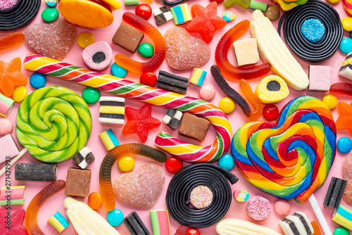 top view of assortment colourful lollipops and candies on pink like background, close up