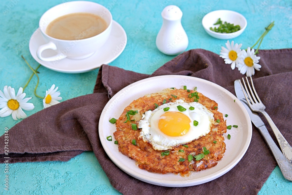 Roshty, fried potato pancake from boiled potatoes with egg on a white clay plate on a turquoise background. Swiss cuisine.
