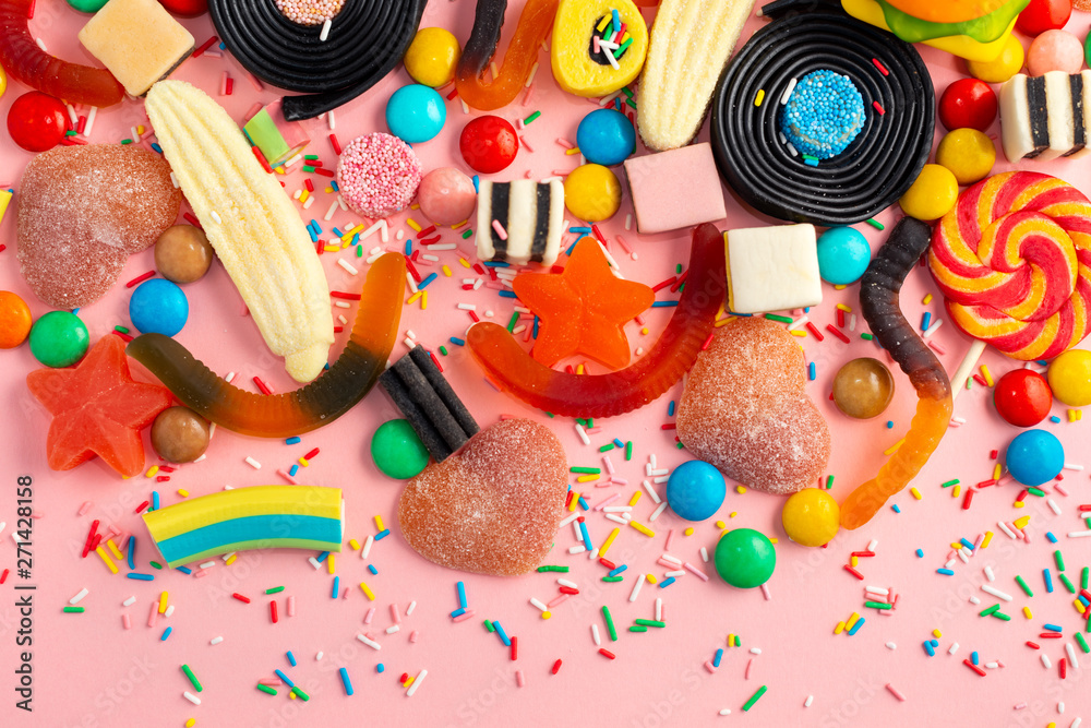 assortment of colourful lollipops, fruit bonbon, candies and sprinkles on pink like background,  copy space
