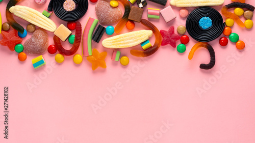 assortment of colourful lollipops and candies on pink like background, copy space, panorama