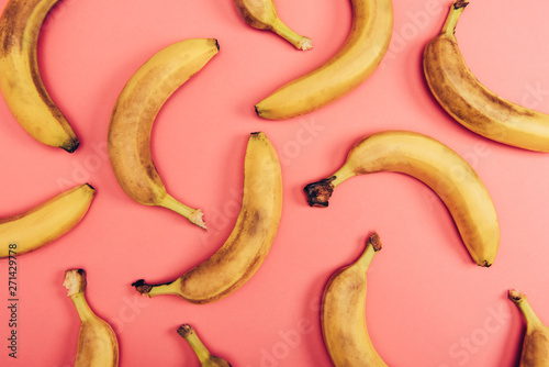 Top view of ripe, bright and yellow bananas on coral background
