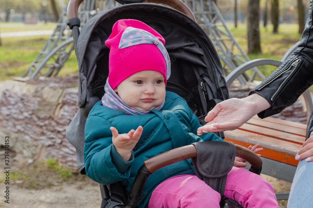 Stylish mother with her daughter in the pram at the bench. Stylish mother with her daughter in the pram at the bench.