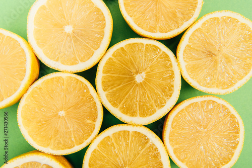 Close up view of bright yellow cut lemons on colorful green background