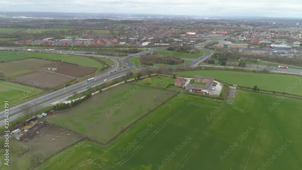 Aerial Drone cars travel from motorway roundabout down main road