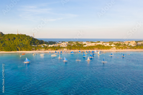 Small sailing boats for touristic excursions at sunset in Boracay island - Exclusive travel destination in Philippines. Blue sailboats on the island of Boracay in the evening.