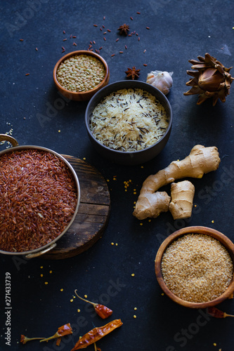 Various types of rice and grains with spices on blue background. Brown rice and mixed wild rice.