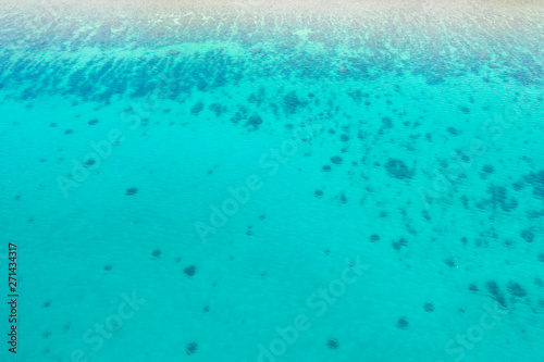 Tropical sea details, blue water in daylight. wallpaper of clear blue tropical sea water with rocks under surface