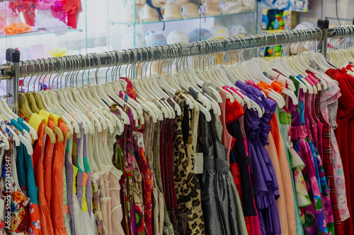 Beautiful colorful clothes in a store on hangers. © combo1982