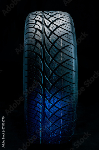 Brand new modern car tyre on a black background. Studio shot