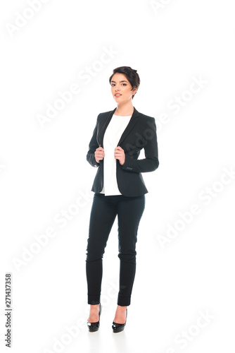 smiling mixed race businesswoman in formal wear looking at camera isolated on white