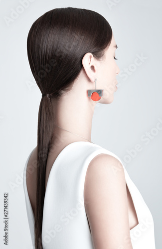 Young stylish woman with earring with orange gemstone