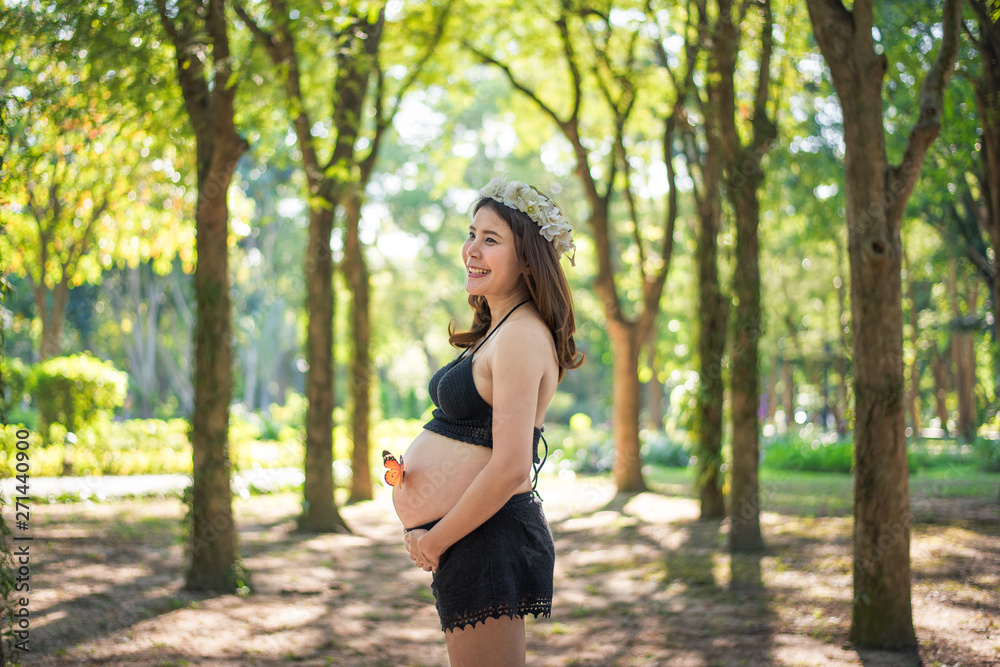 Happy pregnant woman making heart gesture over green natural background Happy pregnant woman making heart gesture over green natural background