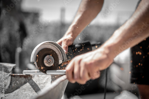 Handwerker schneidet mit dem Winkelschleifer und der Flex Gewindestange auf der Baustelle und die Funken fliegen