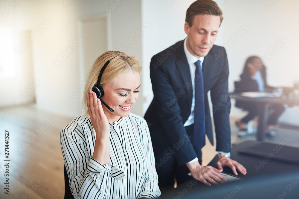 Smiling businesspeople talking with clients over a headset at wo Smiling businesspeople talking with clients over a headset at wo
