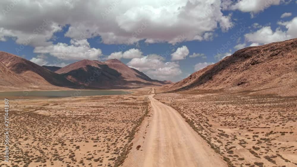 Aerial over gravel off road trail near arid desert mountains in sunny day.Pamir highway silk road trip adventure in Kyrgyzstan and Tajikistan desert,central Asia.4k drone flight establisher video Aerial over gravel off road trail near arid desert mountains in sunny day.Pamir highway silk road trip adventure in Kyrgyzstan and Tajikistan desert,central Asia.4k drone flight establisher video