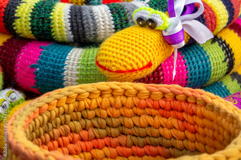 Colorful crocheted handmade toys snake and basket for sale in a souvenir shop on the market. Close-up