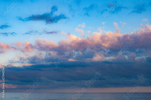 Gorgeous picturesque cloudscape above sunset calm sea in violet dusk evening with blue and lilac clouds in clear light blue sky with touch of pink. Seascape of Black sea coast. Summer cloud landscape  © Ninel