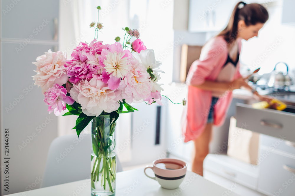 Modern kitchen decorated with pink peonies. Housewife cooking dinner. Interior design. Modern kitchen decorated with pink peonies. Housewife cooking dinner. Interior design.