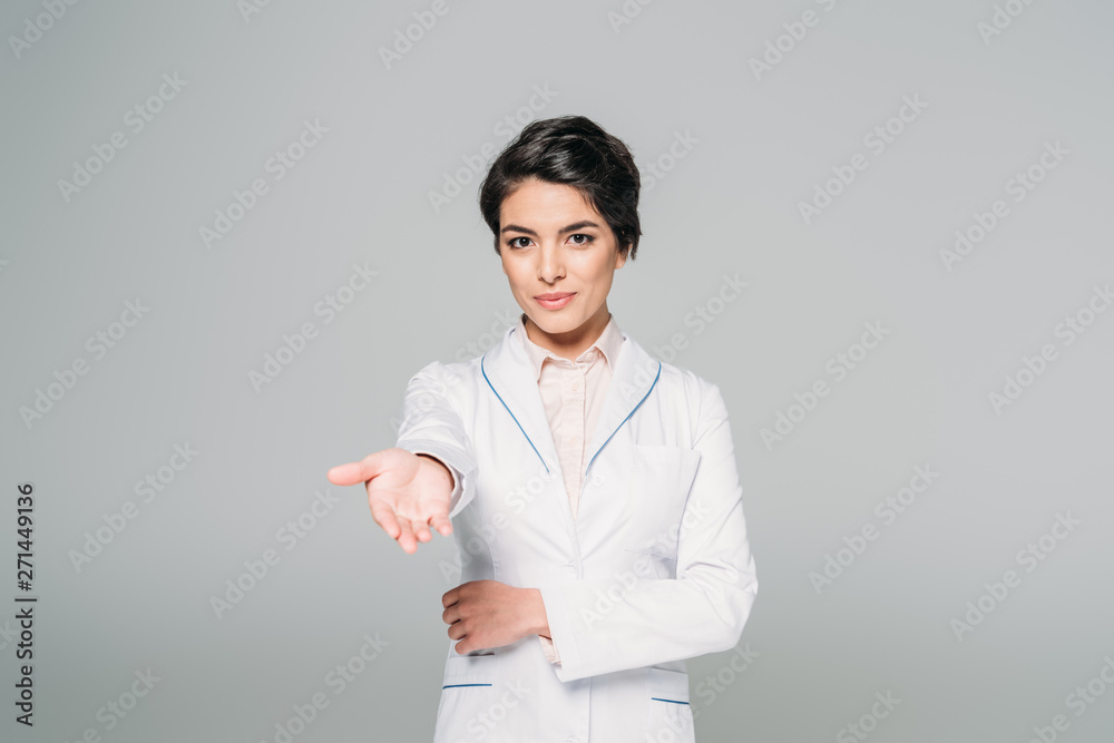 attractive mixed race doctor looking at camera with raised hand isolated on grey attractive mixed race doctor looking at camera with raised hand isolated on grey