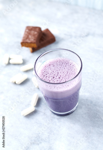 Glass of Protein Shake with Milk and Blueberries, Protein bar in two pieces and Beta-alanine capsules in background. Concept for Sport nutrition. Copy space. 