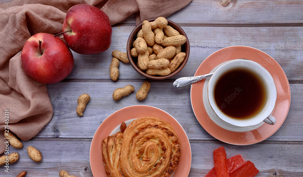 Rustic. Sweet bun. Cup of tea. Peanuts. Red apples. Wood background. Nuts. Fall. Autumnal still life. Top view. Rustic. Sweet bun. Cup of tea. Peanuts. Red apples. Wood background. Nuts. Fall. Autumnal still life. Top view.