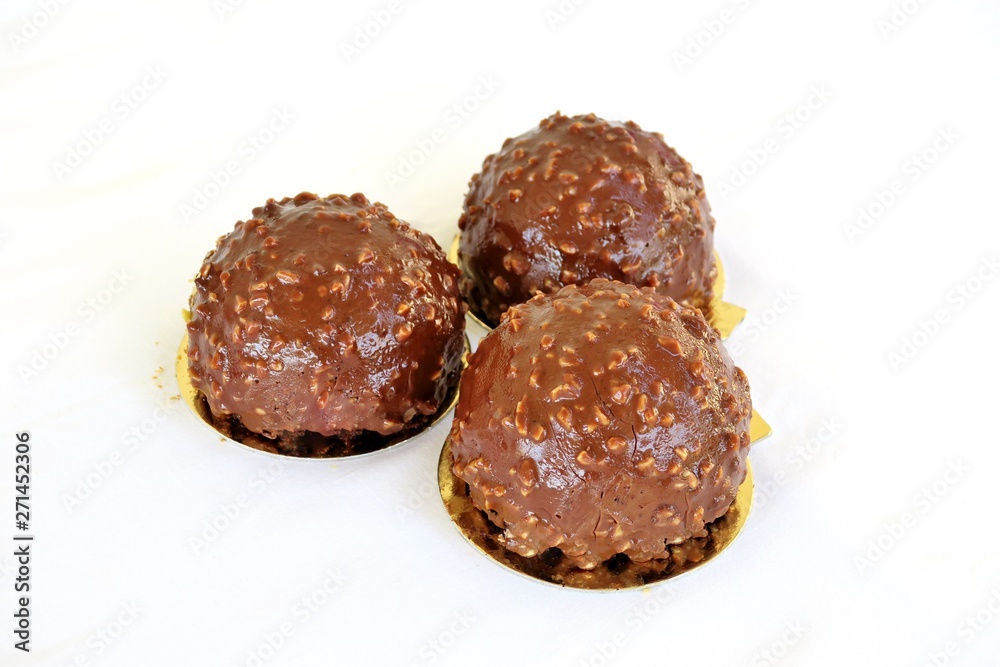 cakes in the shape of a ball drenched in milk chocolate with nuts on a white background cakes in the shape of a ball drenched in milk chocolate with nuts on a white background