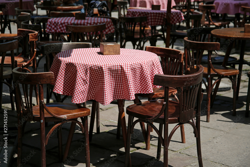 empty wooden chairs and tables in a street cafe