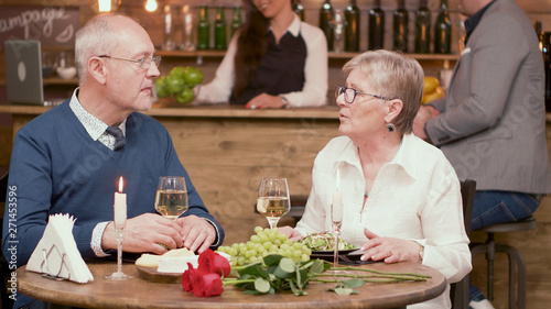 Old couple sitting at the table in a restaurant and drinking wine