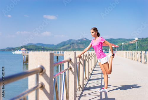 Sport lifestyle. Exercising outdoor. Young pretty woman stretching on the sea shore.