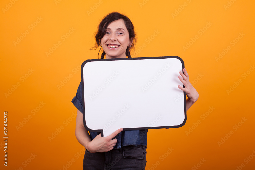 Beautiful young woman smiling and showing copy space available in studio over yellow background Beautiful young woman smiling and showing copy space available in studio over yellow background