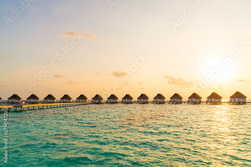 Fototapeta Naklejka Na Ścianę i Meble -  Beautiful tropical sunset over Maldives island with water bungalow in hotel resort