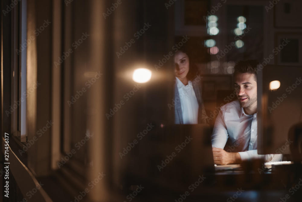 Colleagues working together inside of an office late at night Colleagues working together inside of an office late at night