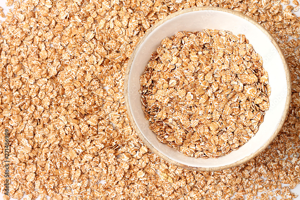 Oat flakes uncooked in wooden bowl on white background. Concept of healthy eating Oat flakes uncooked in wooden bowl on white background. Concept of healthy eating