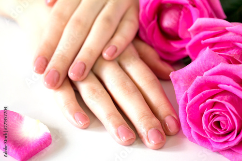 Beautiful manicured woman s nails with pink polish isolated. Manicure  pedicure beauty salon. Beautiful rose red blossoms.