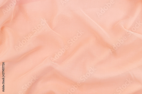 Peach coral soft chiffon fabric texture. Delicate folded cloth silk, organza, crepe chiffon background. Fashion elegant wedding background