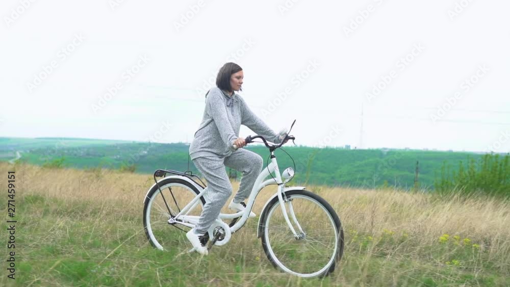 Woman riding white retro bicycle countryside alone Woman riding white retro bicycle countryside alone