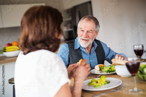 Senior couple in love having lunch indoors at home, talking.