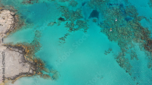 Aerial top view photo of men practising wind surfing in exotic paradise open ocean bay with crystal clear turquoise sea