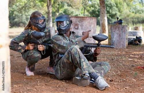 Two opposing teams shooting on paintball playing field outdoors