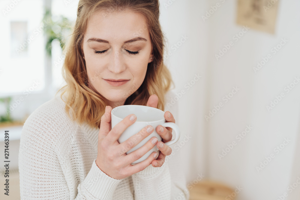 frau genießt eine tasse mit heißem kaffee und schließt die augen