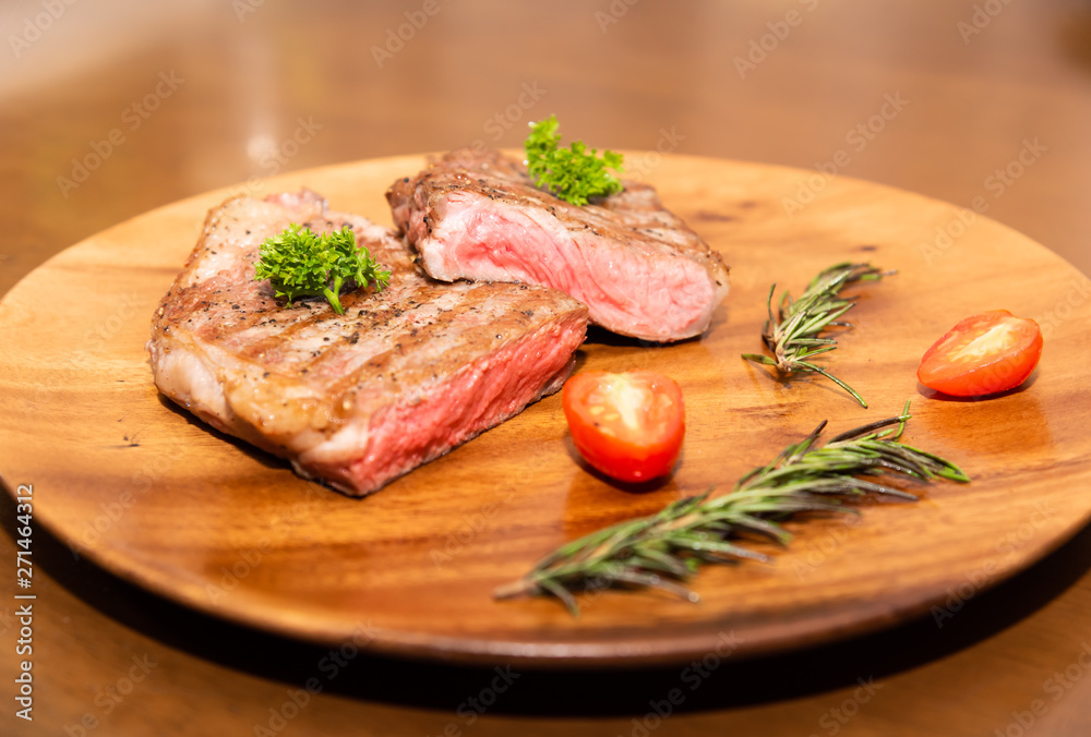 Fresh cooked half cut beef sirloin with cherry tomato and rosemary on top with parsley, Wood background