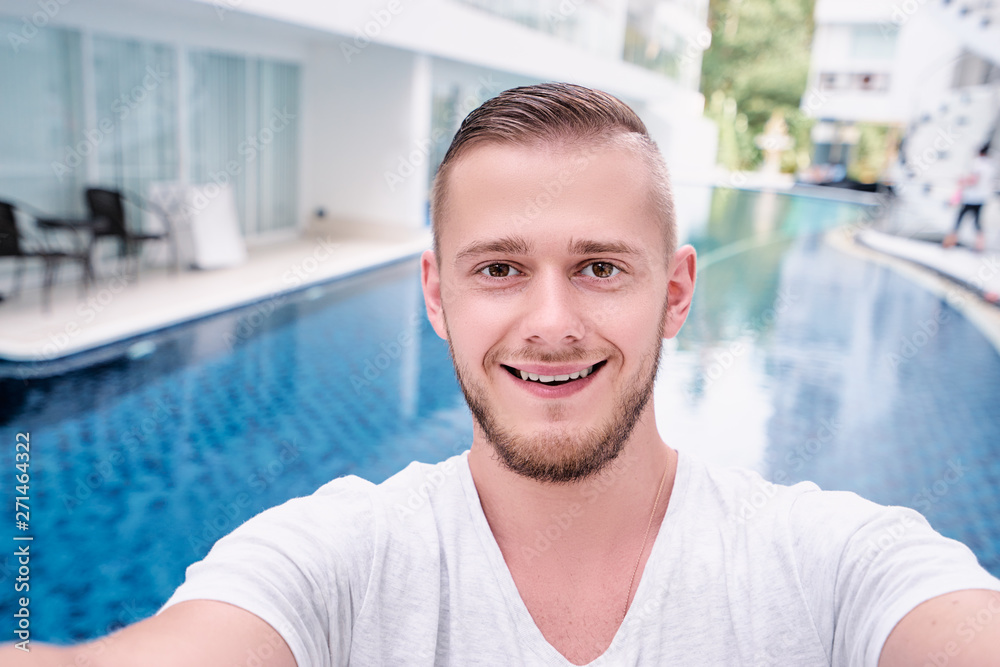 Youth and technology. Handsome young man taking selfie on swimming pool background.