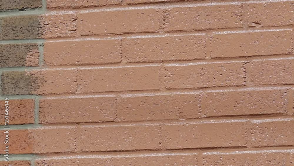 Cleaning graffiti from a wall. Painting brick wall with paint roller