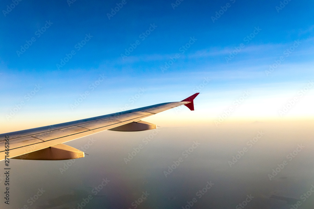 Fototapeta premium Airplane flying in cloudy over sky. Spectacular view of horizon during sunset from plane.