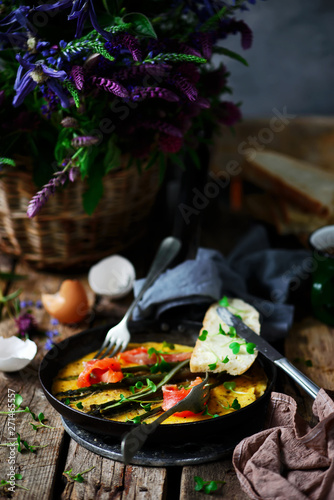 Omelet with asparagus and salmon in iron pan