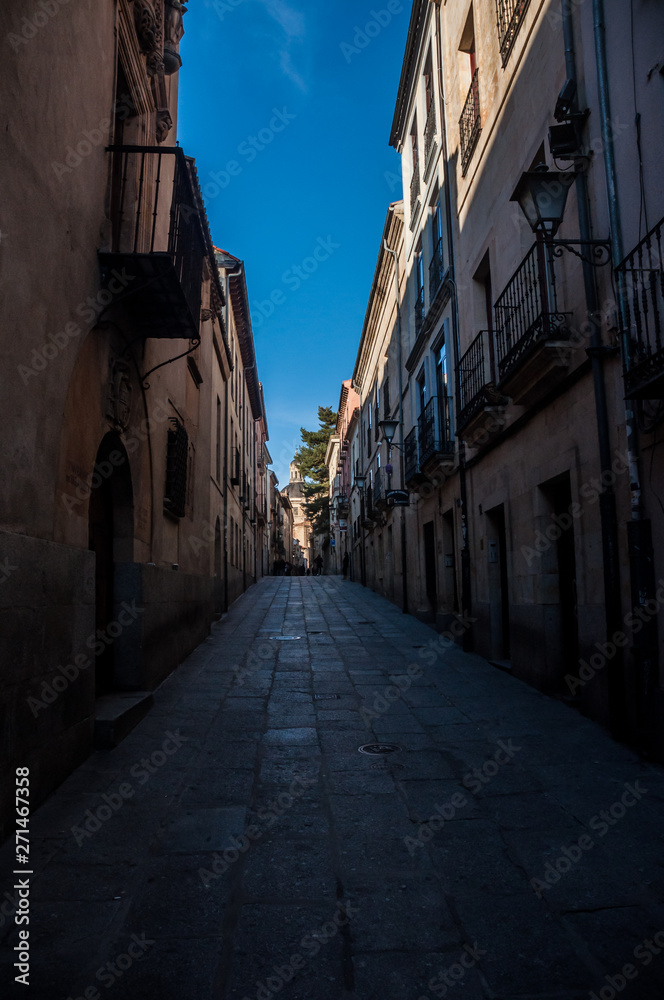 Calle estrecha antigua empedrada con casas y balcones en Salamanca